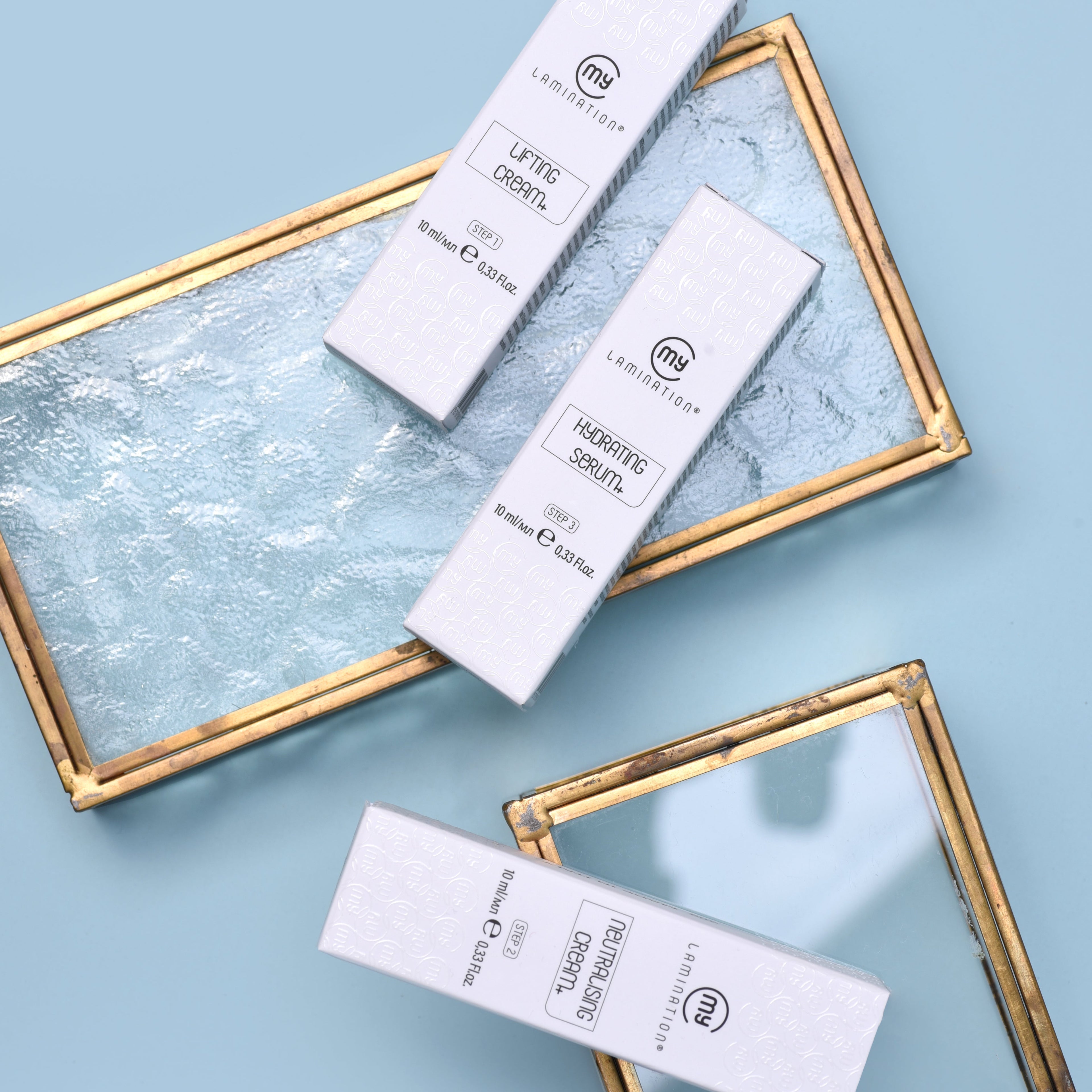 Three skincare product boxes on a textured blue surface with gold frames.